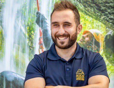 Man smiling in navy shirt with nature background.