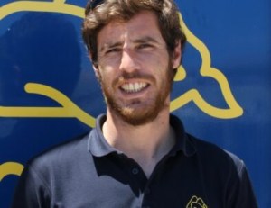Man in navy polo shirt against blue background with yellow design.