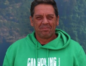 Man in green hoodie smiling outdoors.