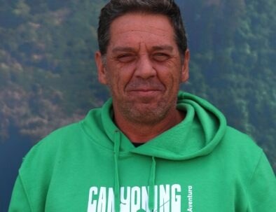 Man in green hoodie smiling outdoors.