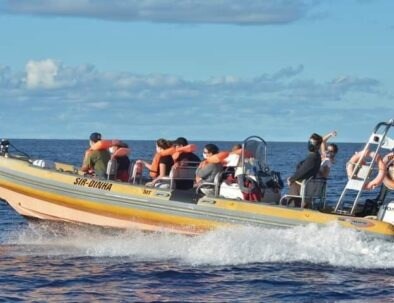 A group of people wearing life jackets on a motorboat in the ocean.
