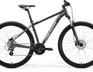 Black Merida mountain bike with thick tires, disc brakes, and a sleek frame.