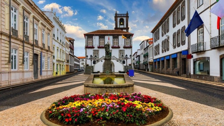 Colorful flowers in front of a historic town square with European architecture.