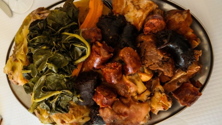 Plate with assorted meats, greens, and vegetables.