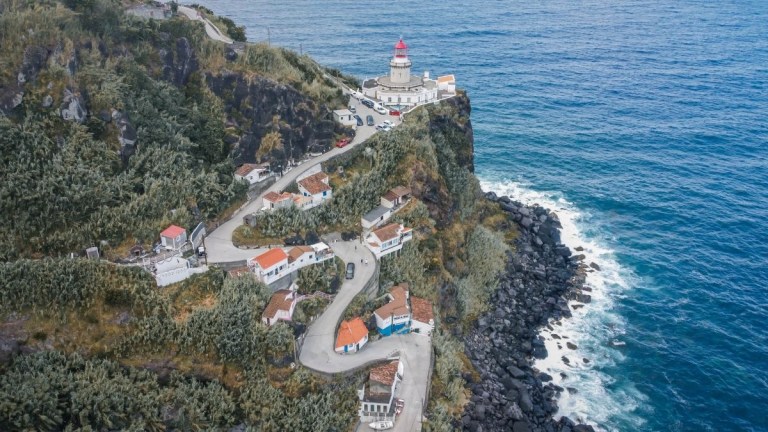 Cliffside lighthouse with winding road and ocean view