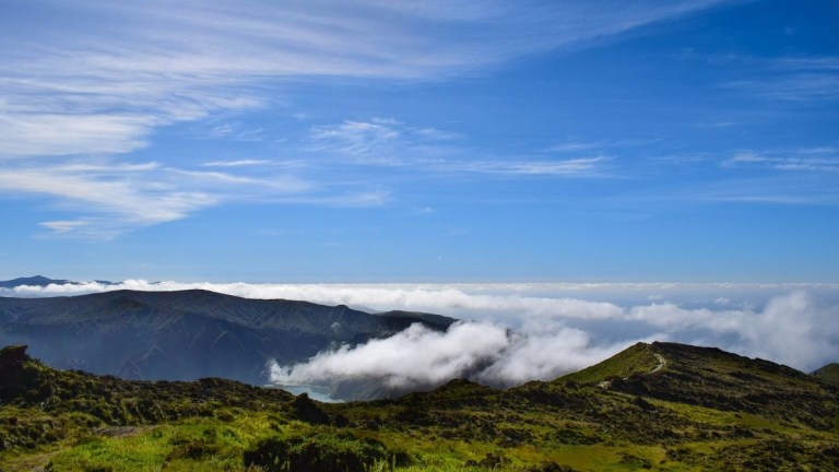 Mountain landscape with clouds over peaks and blue sky.