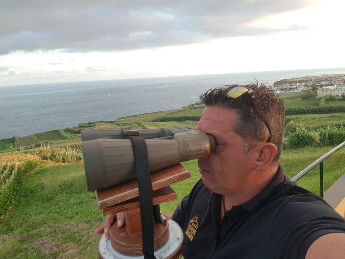 Person looking through large binoculars at ocean view.