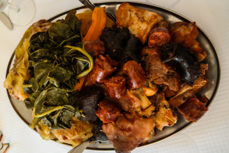 Platter of mixed meats, sausages, greens, and vegetables.