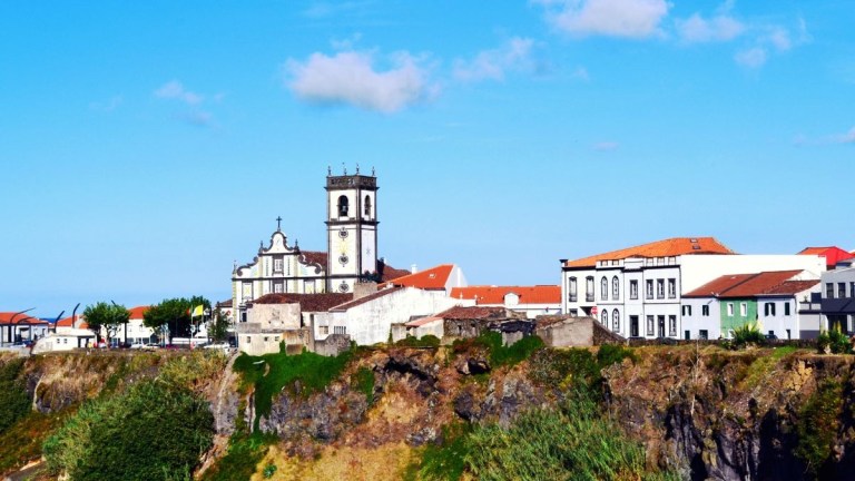 Historic buildings on a cliff under a blue sky.