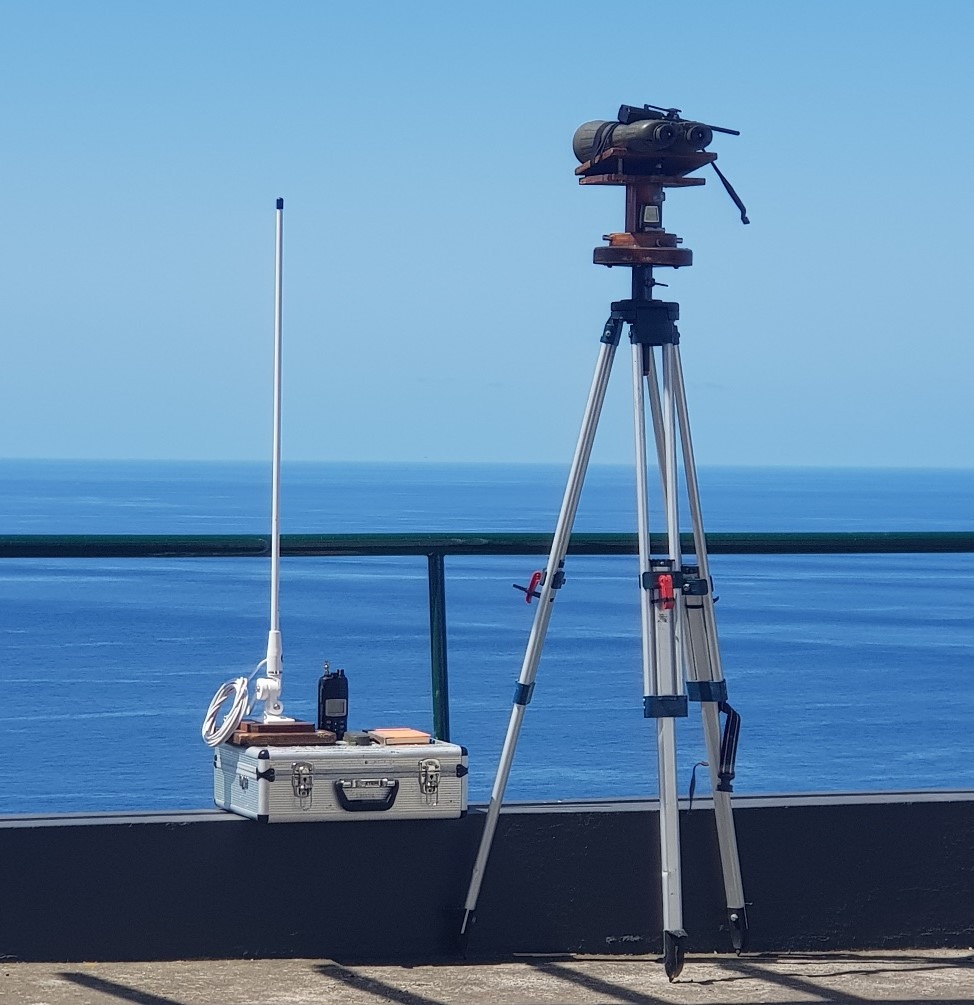 Tripod and equipment by ocean on sunny day.