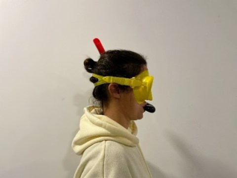 Person in hoodie wearing a yellow snorkel mask and snorkel against a plain background.