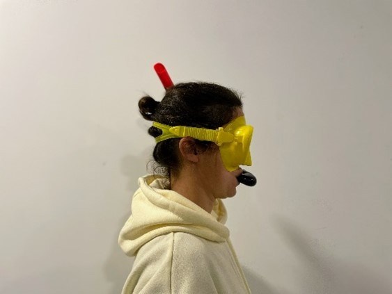 Person in hoodie wearing a yellow snorkel mask and snorkel against a plain background.