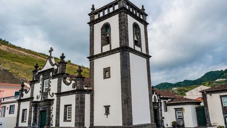 Historic church with bell tower and stone accents under a cloudy sky.