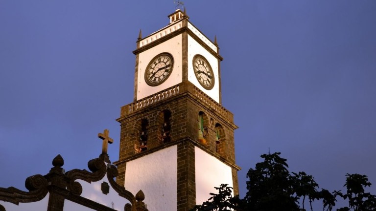 Clock tower with illuminated white facade at dusk.