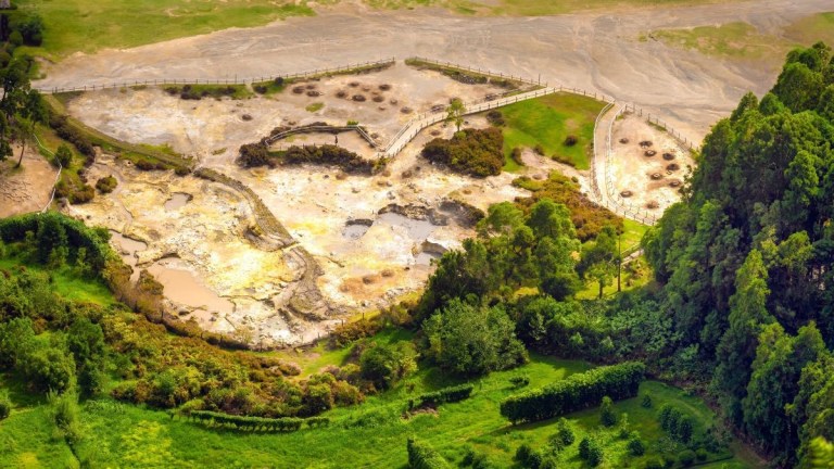 Aerial view of a patchy mudflat with surrounding greenery and wooden walkways.