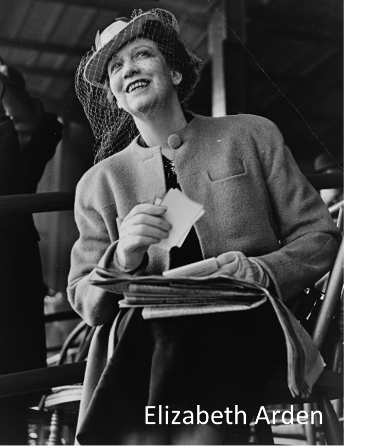 Smiling woman in a coat and hat, holding papers, seated outdoors.