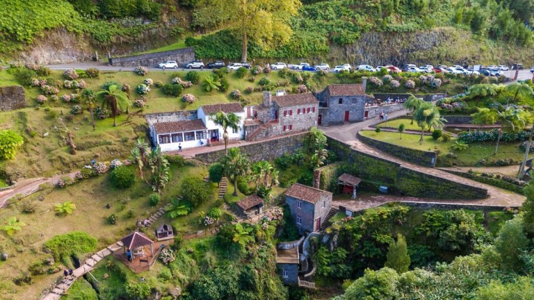 Aerial view of a hillside village with stone houses and gardens.