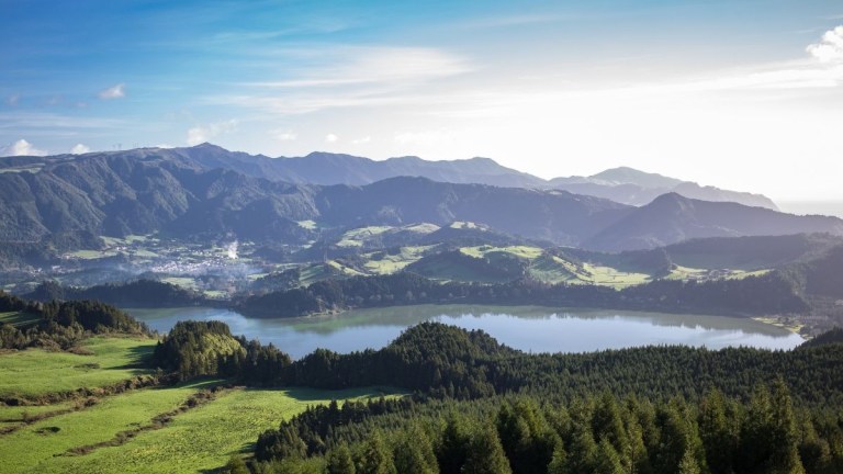 Scenic view of mountains, lake, and forest under a clear blue sky.