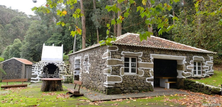 Stone houses and picnic area surrounded by trees.