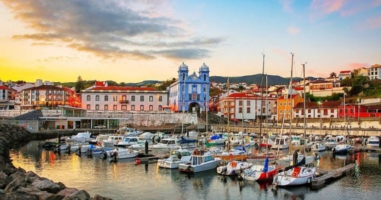 Colorful boats in a marina with colorful buildings at sunset.