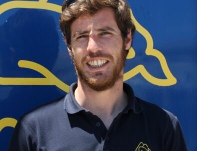 Man in navy polo shirt against blue background with yellow design.