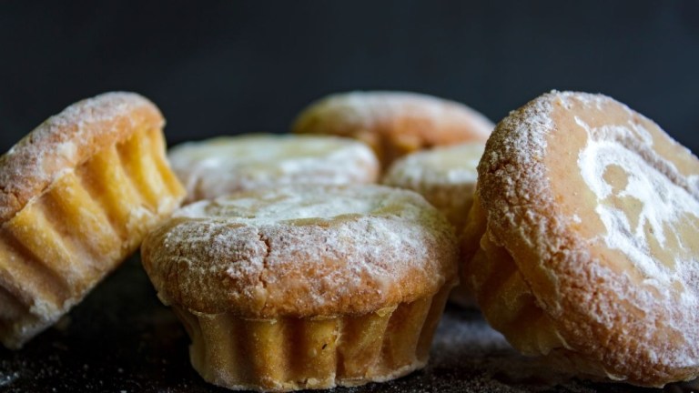 Powdered sugar dusted muffins on a dark background.