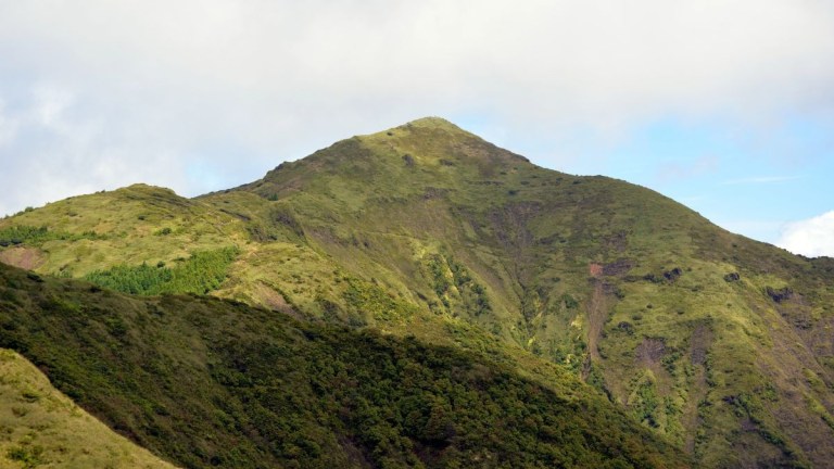 Lush green mountain peaks under a cloudy sky