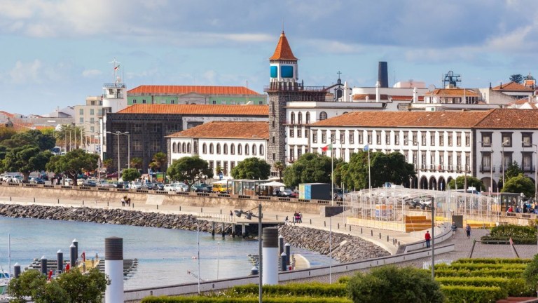 Scenic coastal view of a town with historic buildings and a blue clock tower.