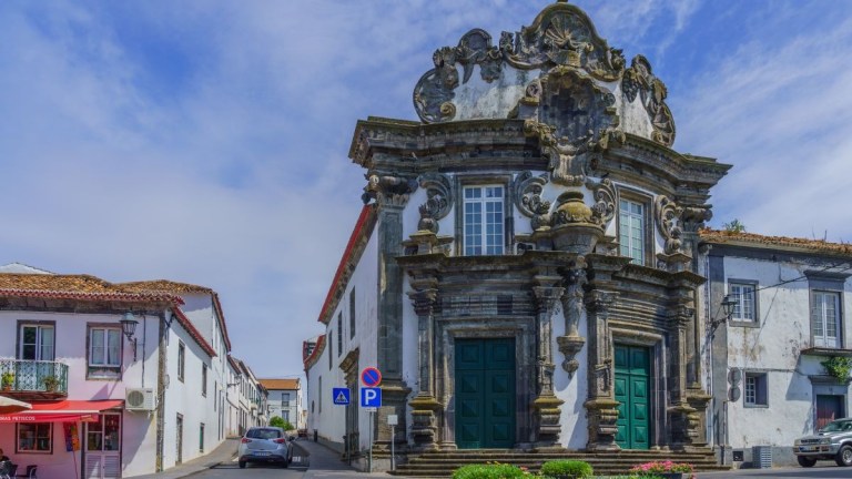 Ornate historical building with detailed facade and classical columns on a quiet street.