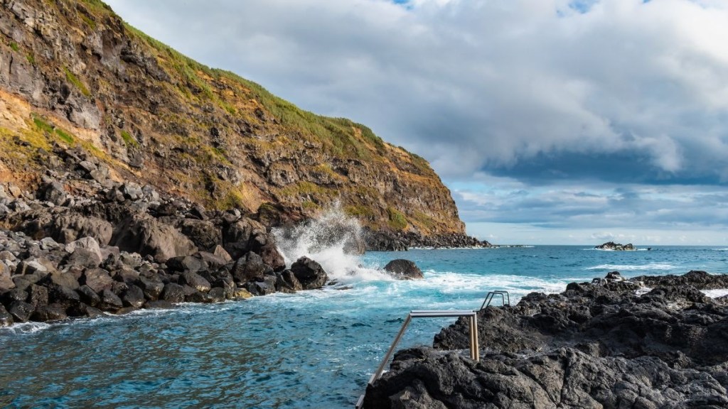 Rocky coastline with waves crashing and a ladder into the sea