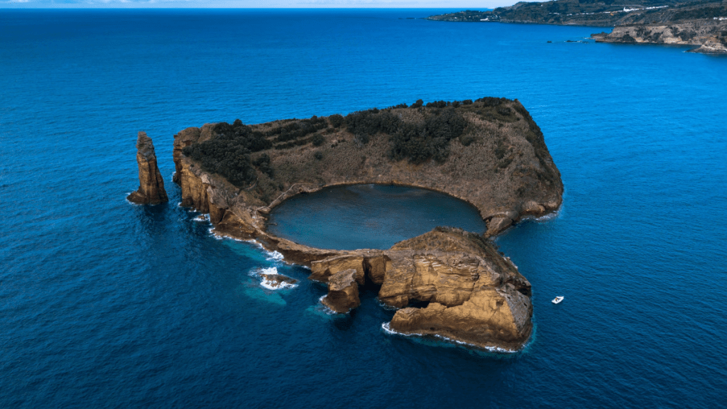 Aerial view of island with a crater lake surrounded by ocean.