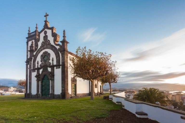 Historic church with ornate facade on a grassy hilltop at sunset.