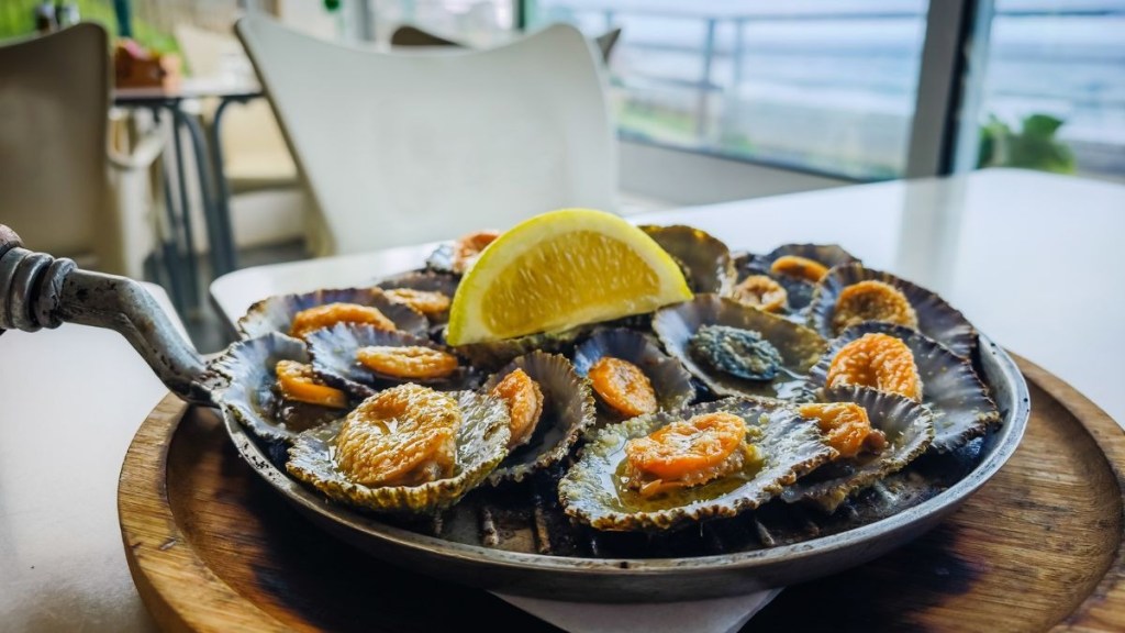 Grilled shellfish with lemon slice on a plate in a restaurant.