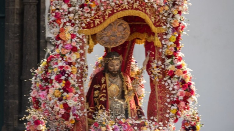 Statue of religious figure adorned with a colorful floral arch.