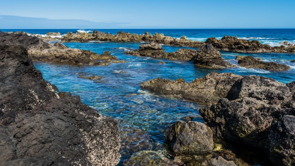 Rocky coastline with clear blue water under a clear sky.