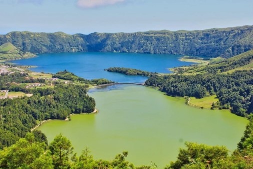 Two lakes with different colors surrounded by green hills and trees.