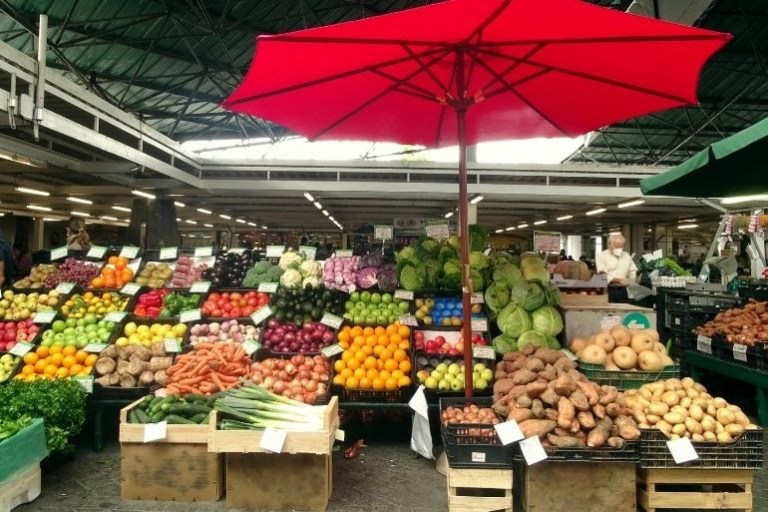 Fruit and vegetable market stall with red umbrella.