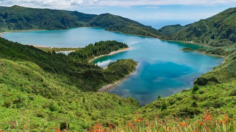 Scenic view of a turquoise lake surrounded by lush green hills.