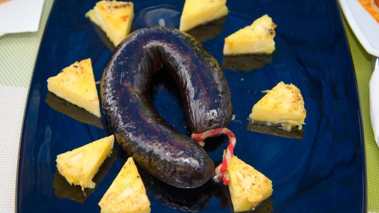 Sausage with pineapple slices on a blue plate.