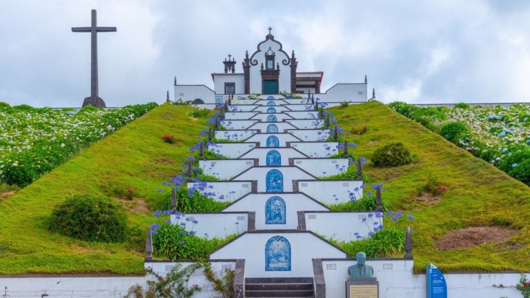 Chapel and cross atop a hillside with stairs and blue tile accents.