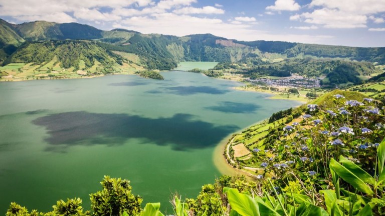 Scenic view of a lake surrounded by green hills and a small village.