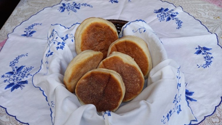 Basket of muffins on floral tablecloth.
