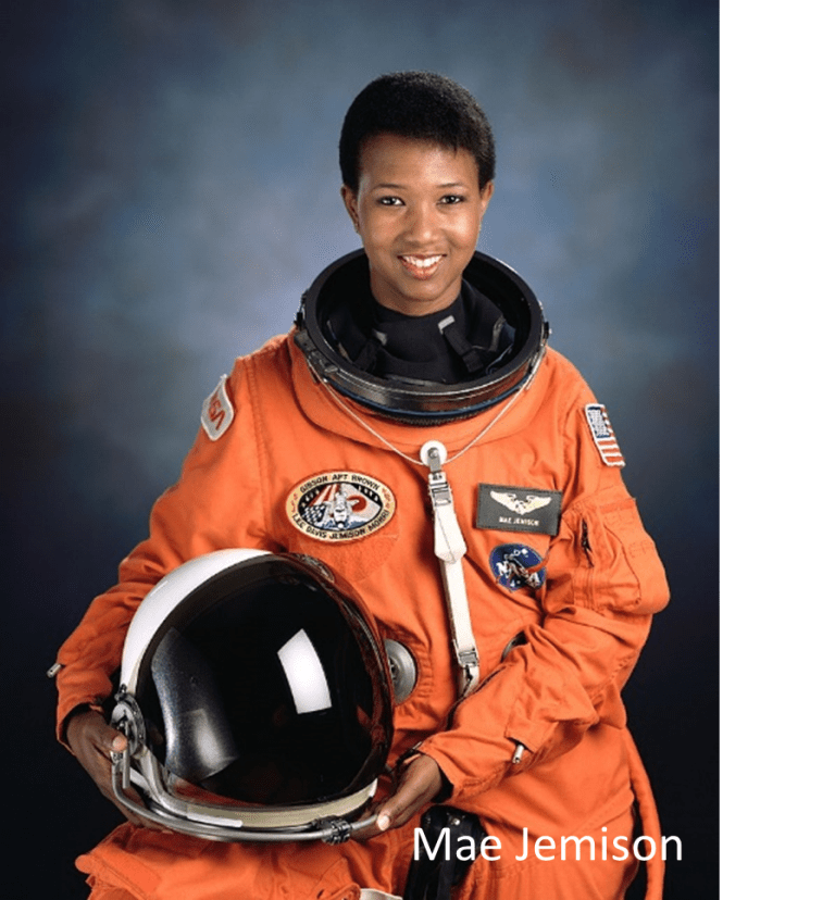 Astronaut in an orange suit holding a helmet.