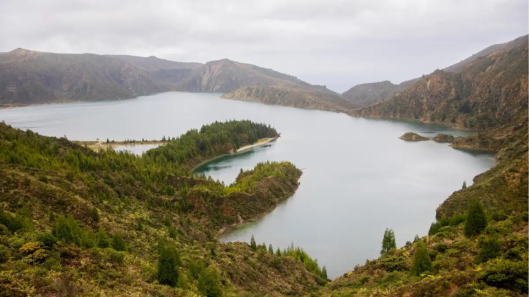 Mountainous lake landscape with cloudy sky and lush greenery.